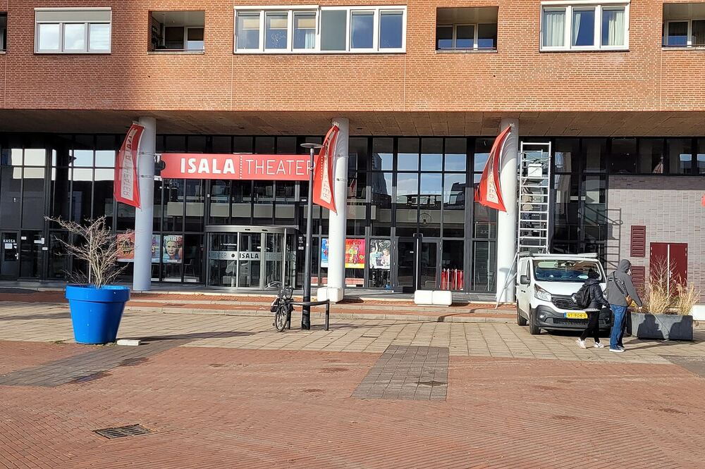 De ingang van het Isala Theater aan het Stadsplein in Capelle aan den IJssel, met rode theatervlaggen en blauwe plantenbakken